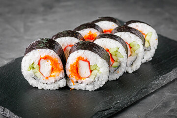 appetizing sushi roll futomaki with cucumber crab stick and masago on a black stone plate