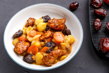 A dish of Jewish cuisine sweet tsimes with vegetarian dates carrots in a plate on stand next to candied fruits