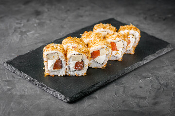 appetizing sushi roll with tuna cheese and tofu on a black stone plate