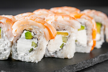 appetizing sushi roll philadelphia with avocado cheese cucumber and shrimp on a black stone plate