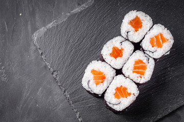 appetizing sushi roll maki with salmon on a black stone plate