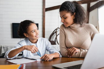 Obraz premium african american girl doing homework near happy mother