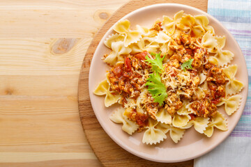 Pasta in tomato bolognese sauce in a plate on a napkin next to a fork. copy space