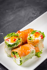 appetizing spring rolls with sea food and philadelphia cheese on a darck background