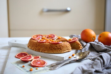 Sponge cake with red oranges on gray background