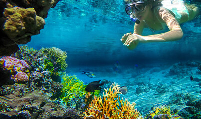 girl snorkeling underwater in the sea corals and fish