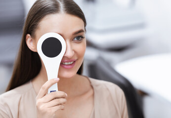 Smiling female patient doing eye test in clinic