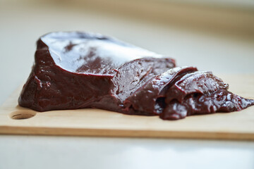A piece of beef liver on a chopping board. Selective focus.