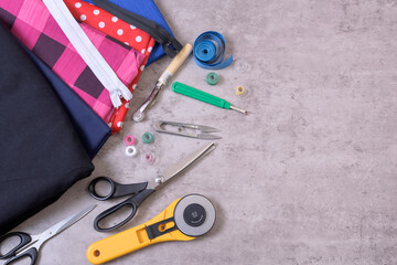 Sewing items and accessories for needlework, fabric, thread, scissors, clasp, cutter, tape measure, on gray background