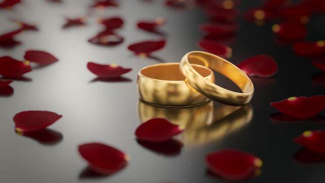 Two gold wedding rings laying on a shiny black surface while red rose petals are falling down. 3D Rendered Video