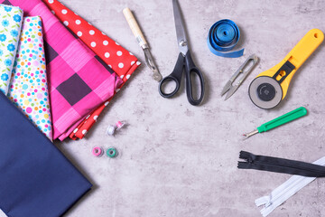 Sewing items and accessories for needlework, fabric, thread, scissors, clasp, cutter, tape measure, on gray background