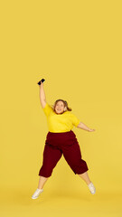 Plakat Jumping high. Beautiful plump caucasian plus size model isolated on yellow studio background. Concept of inclusion, human emotions, facial expression, sales, body positive. Copyspace for ad.