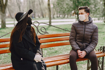 People in the city. Persons in a masks. Coronavirus theme. Couple sitting on a bench.