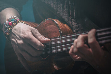 Hands of a man playing the ukulele. Folk music performer on ukulele. Photo with toning and shallow...