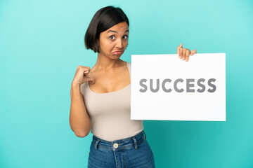 Young mixed race woman isolated on blue background holding a placard with text SUCCESS with proud gesture