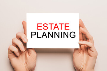 Female hands hold card paper with text Estate Planning on a yellow background. Business and finance concept
