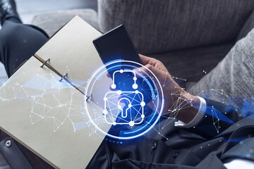 A programmer is browsing the Internet in smart phone to protect a cyber security from hacker attacks and save clients confidential data. Padlock Hologram icons over the typing hands. Formal wear.
