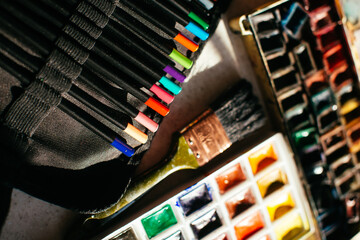 Desk of an artist with watercolor paints and paintbrushes, Color pencils