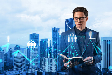 Handsome eastern HR director at international company is looking into personal organizer to plan business meeting to recruit highly qualified specialists. Social media hologram icons over Kuala Lumpur