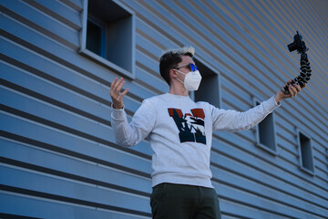 Young blogger man wearing face mask due to covid19 recording himself in the street.