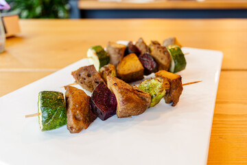 Vegan meal. Grilled skewers with mixed vegetables and seitan served on a white plate
