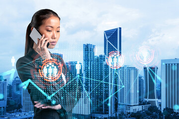 Attractive Asian businesswoman processing conference call to develop social media marketing strategy to achieve business goals. Hologram icons over Kuala Lumpur background.