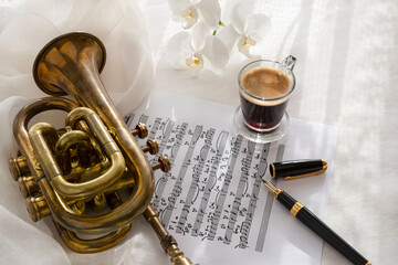 Naklejka premium Black coffee cup on a music score with trumpet and flower 