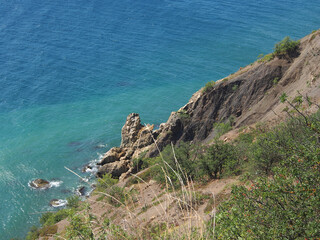 View of the rocky seashore. Fantastic view of the rocky shore on a sunny day with blue sky. A picturesque and magnificent scene. The concept of active recreation, travel.