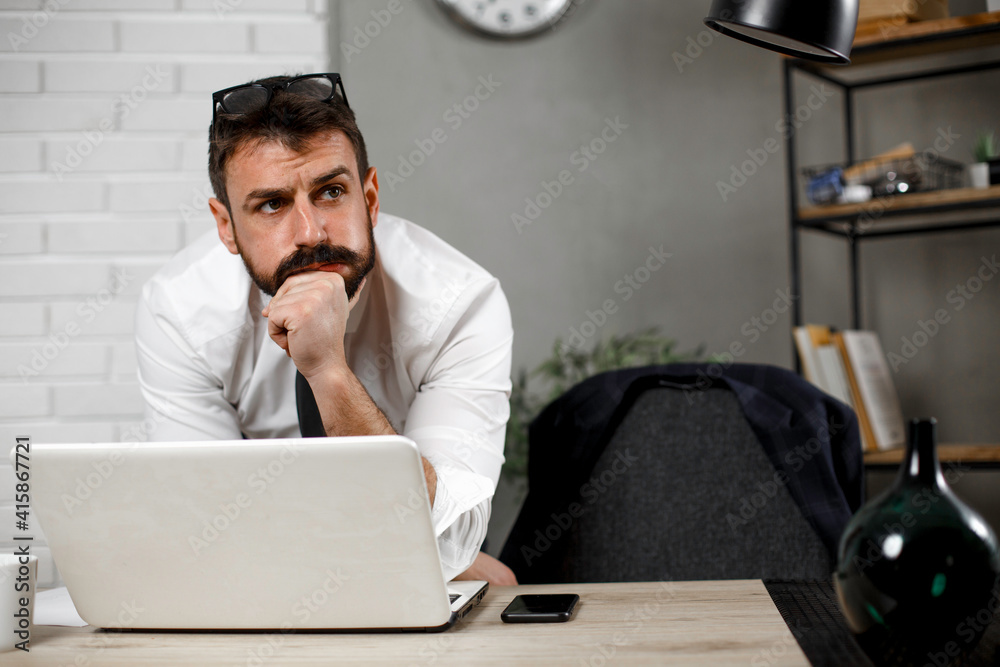 Wall mural Young businessman using laptop in his office. Happy man working on computer at his workplace..