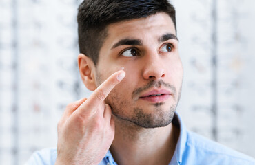 Young guy wearing contact eye lenses, looking up