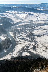 A village in a winter scenery by a river in the Polish Pieniny Mountains seen from above.