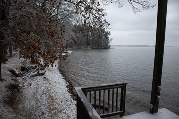 coastline of lake in alabama during snow storm with trees, waves, boat dock, mountains