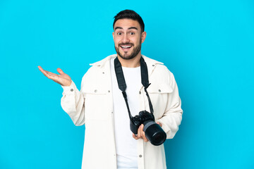 Young photographer man isolated on blue background with shocked facial expression