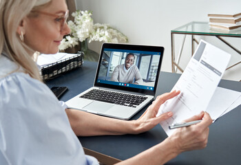 Female hr reading cv during online virtual job interview by video call. Employer checking african...