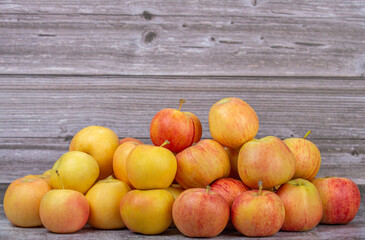 heap of golden and striped apples on wooden background