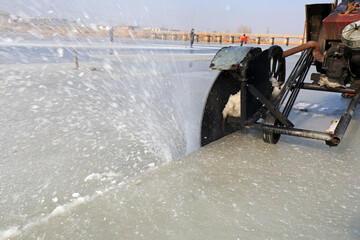 Farmers use electric saws to cut river ice in the wild.