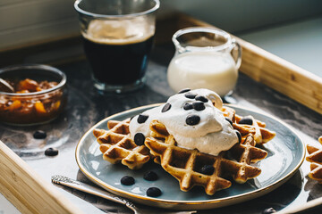 Homemade Belgian waffles with natural whipped cream, chocolate droplets and apricot jam,  glass of...