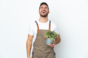 Gardener man holding a plant isolated on white background laughing