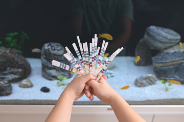 Science. A boy is holding test ph strips to test the water in the aquarium
