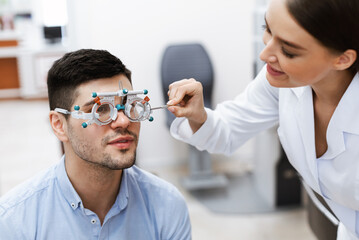 Optometrist checking male patients vision with trial frame