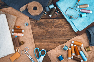 Fabrics, threads and scissors with a ribbon on a natural wooden background. The concept of sewing accessories.