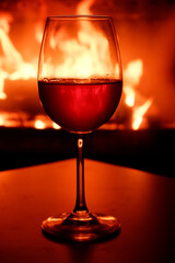 Close-up of a glass of white wine in the backlight of a burning fireplace.