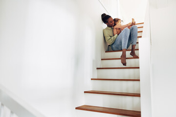 Mom reading a story to her little girl on stairs at home - Powered by Adobe