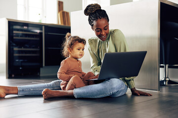 Smiling mother and little girl watching something on a laptop