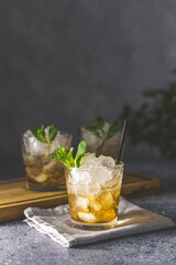 Close up of a mint julep served on light gray table surface and garnished with fresh green mint on top, kentucky derby drink