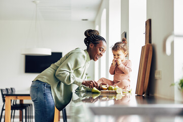 Smiling mom and her cute little daughter eating a healthy snack - 415877128