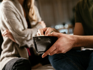 Young man checking empty wallet, no money. Unemployed sad man sitting at home showing empty wallet..