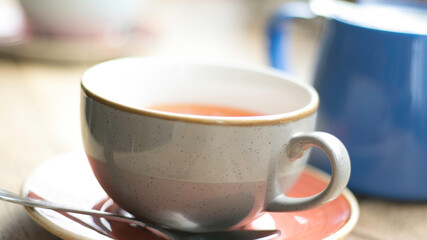 Interior view of British traditional tea room, city life, details of a cup on the wooden counter, natural daylight. 
