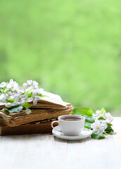 tea cup, old books and apple flowers on table in garden. romantic atmosphere tea time. spring season