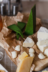 Delicious cheeses on a board with honey and wine on a paper background